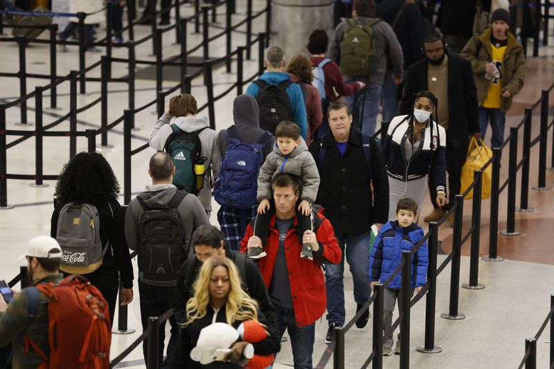 Travelers stand in line going through a security checkpoint at Hartsfield-Jackson Atlanta International Airport ahead of Christmas weekend. Hartsfield-Jackson advises travelers to get to the airport 2.5-3 hours before their flights. Miguel Martinez / miguel.martinezjimenez@ajc.com