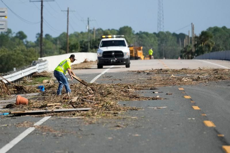 Workers remove debris in the aftermath of Hurricane Helene, in Cedar Key, Fla., Friday, Sept. 27, 2024. (AP Photo/Gerald Herbert)