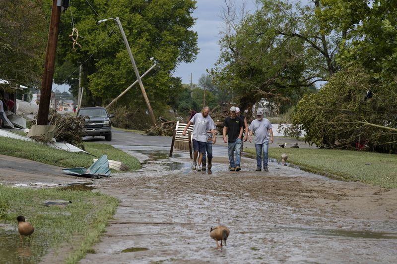 People walk along River St. flood damage is seen Saturday, Sept. 28, 2024, in Newport, Tenn. (AP Photo/George Walker IV)