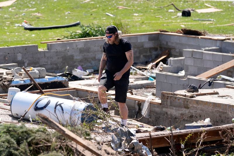 Tom Wiggins sorts through debris at his grandparents' tornado-damaged home, Thursday, May 23, 2024, in Greenfield, Iowa. (AP Photo/Charlie Neibergall)