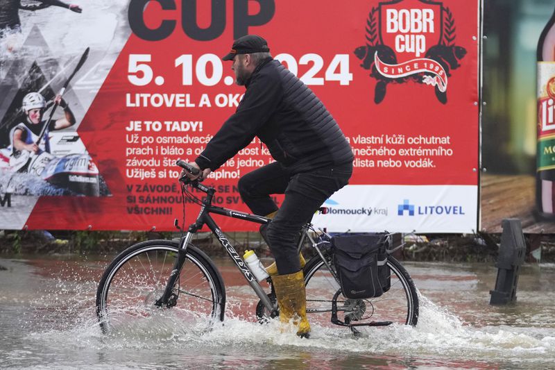 A resident rides a bicycle through a flooded street in Litovel, Czech Republic, Monday, Sept. 16, 2024. (AP Photo/Petr David Josek)