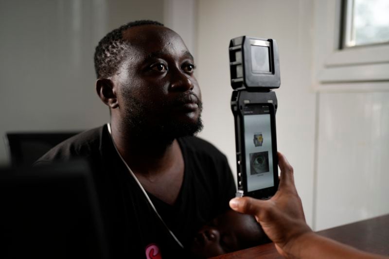 A Panamanian immigration officer does a biometric check on William Kanana, from the Democratic Republic of the Congo, at a post in Lajas Blancas, Panama, where migrants who have trekked across the Darién Gap are processed, Thursday, Sept. 26, 2024. (AP Photo/Matias Delacroix)