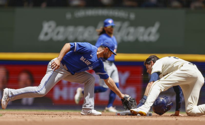 Milwaukee Brewers outfielder Christian Yelich (22) slides into second with a stolen base ahead of the throw to Toronto Blue Jays' Isiah Kiner-Falefa in the first inning of a baseball game Wednesday, June 12, 2024, in Milwaukee. (AP Photo/Jeffrey Phelps)