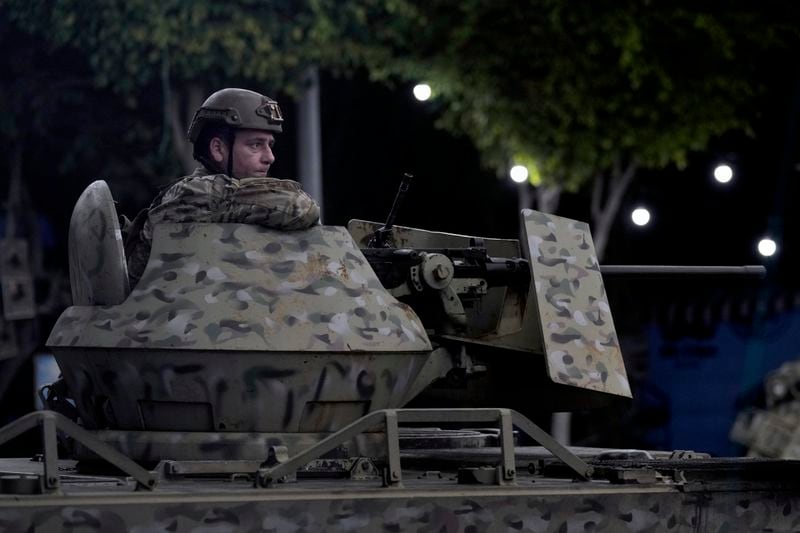 A Lebanese army soldier sits behind his weapon on the top of an armored personnel carrier at the site of an Israeli airstrike in Beirut's southern suburb, Monday, Sept. 23, 2024. (AP Photo/Bilal Hussein)