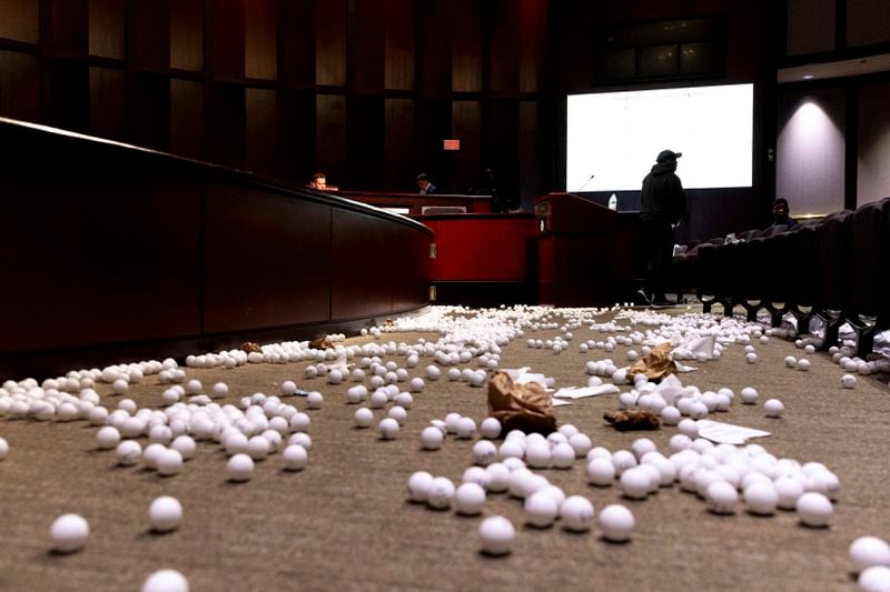 Ping pong balls litter the floor after opponents of the under-construction law enforcement training center known to some as Cop City disrupted the City Council meeting at City Hall in Atlanta on Monday, Sept. 16, 2024. (Arvin Temkar/Atlanta Journal-Constitution via AP)