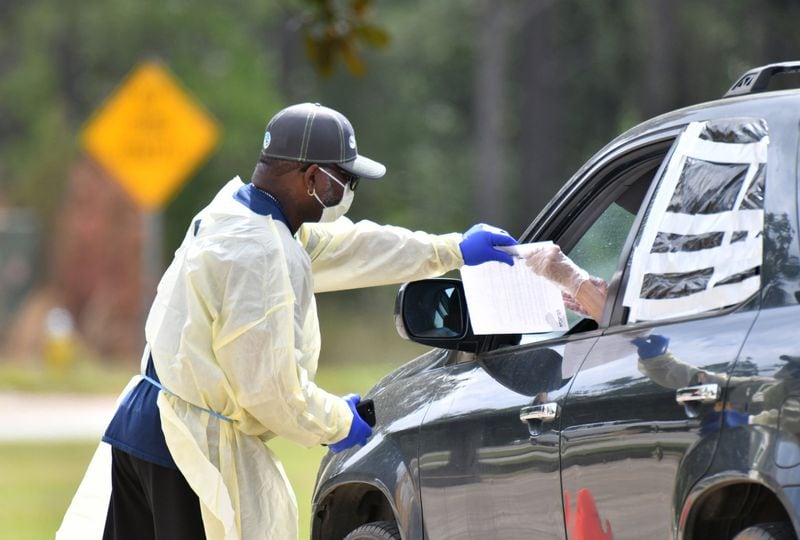 A medical worker helps a potential COVID-19 patient with paperworks at a Phoebe Putney Health System drive-through testing site in Albany on Tuesday, March 24, 2020. Albany is home to one of the worst outbreaks in the world based on death rate. HYOSUB SHIN / HYOSUB.SHIN@AJC.COM