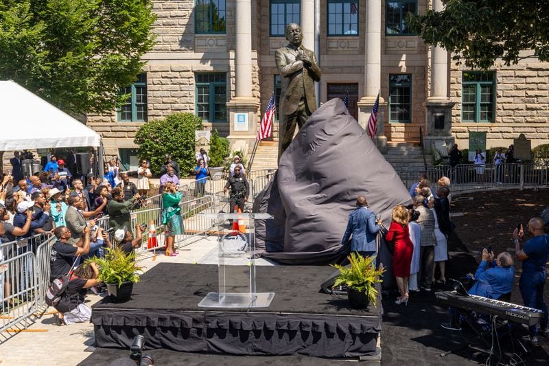 Dignitaries pull the cover off the statue during the unveiling ceremony honoring the late Congressman John Lewis in Decatur on Saturday, Aug 24, 2024.  (Steve Schaefer / AJC)