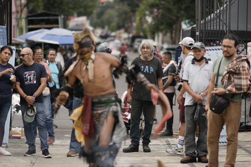 People watch as Mexica dancers perform during a ceremony commemorating the 503rd anniversary of the fall of the Aztec empire's capital, Tenochtitlan, in Mexico City, Tuesday, Aug. 13, 2024. (AP Photo/Eduardo Verdugo)