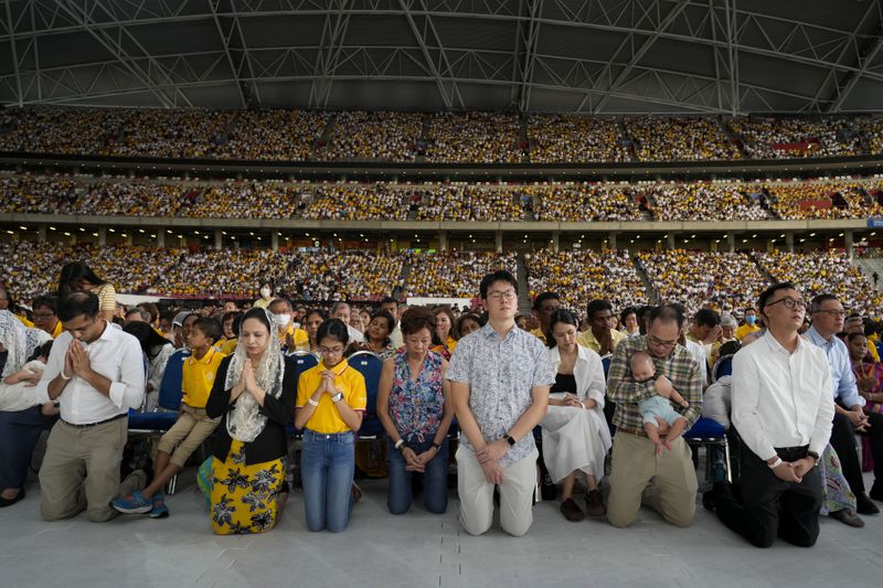 The faithful follow Pope Francis presiding over a mass 'In Memory of the Most Holy Name of Mary' celebrated by the Archbishop of Singapore, Cardinal William Goh Seng Chye at the Singapore SportsHub National Stadium, Thursday, Sept. 12, 2024. In the farthest trip of his pontificate and one of the longest papal trips ever in terms of days on the road and distance traveled, Pope Francis, age 87, hobbled by bad knees and bent over with sciatica, appeared to be having the time of his life. (AP Photo/Gregorio Borgia)