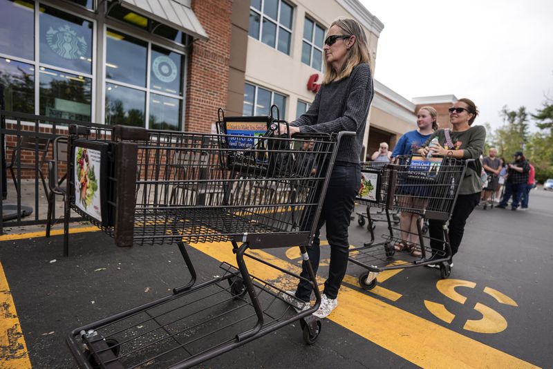 People wait to buy groceries as they stand in line outside an Ingles grocery store in the aftermath of Hurricane Helene, Monday, Sept. 30, 2024, in Asheville, N.C. (AP Photo/Mike Stewart)