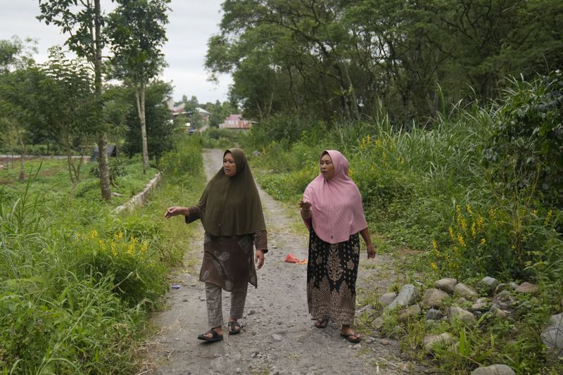Female rangers Sumini and Rosita walks on a village pathway in Damaran Baru, Aceh province, Indonesia, Monday, May 6, 2024. The female-led group of forest rangers are defying social norms to lead patrols in the jungle to combat deforestation. (AP Photo/Dita Alangkara)