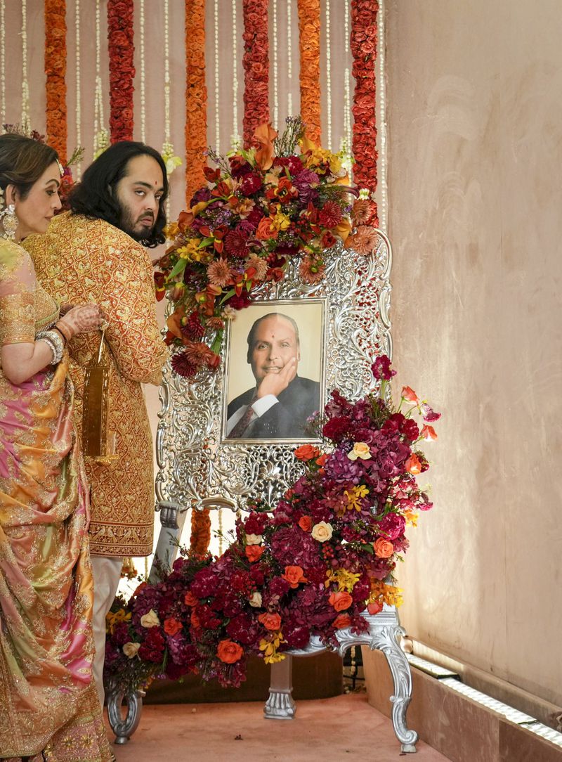 Billionaire Mukesh Ambani's son Anant and wife Neeta stand in front of a portrait of Mukesh's father Dhirubhai Ambani to pay their respects, at the wedding of Anant Ambani and Radhika Merchant at Jio World Convention Centre in Mumbai, India, Friday, July 12, 2024. (AP Photo /Rajanish Kakade)