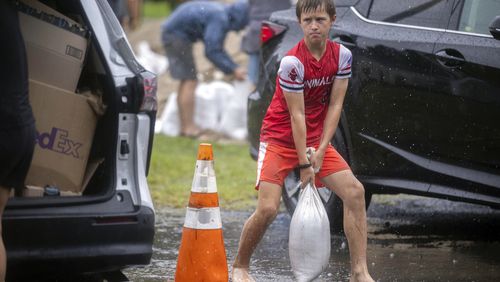 Brantley Schnabel helps his family carry sandbags to their van while preparing for Hurricane Debby at a county park, Monday, Aug. 5, 2024, in Savannah, Ga. Debby reached the Big Bend coast of Florida early Monday, bringing with it the potential for catastrophic flooding and life-threatening storm surge. (AP Photo/Stephen B. Morton)