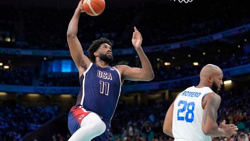 United States' Joel Embiid, left, goes up for a dunk as Puerto Rico's Ismael Romero defends during a men's basketball game at the 2024 Summer Olympics, Saturday, Aug. 3, 2024, in Villeneuve-d'Ascq, France. (AP Photo/Michael Conroy)