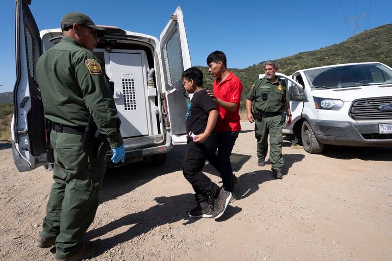 FILE - Border Patrol agents lead a group of migrants seeking asylum towards a van to be transported and processed, Wednesday, June 5, 2024, near Dulzura, Calif. President Joe Biden has suspended asylum processing at the U.S. border under a new policy unveiled this week. But the proclamation has an exception for “operational considerations.” The Homeland Security Department said in a detailed document outlining the ban that “demographics and nationalities encountered at the border significantly impact” its ability to deport people. (AP Photo/Gregory Bull, File)