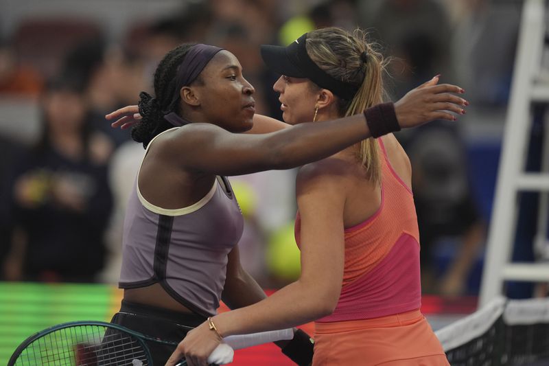 Coco Gauff of the United States left hugs Paula Badosa of Spain after their women's singles semi-final match for the China Open tennis tournament held at the National Tennis Center in Beijing, Saturday, Oct. 5, 2024. (AP Photo/Ng Han Guan)