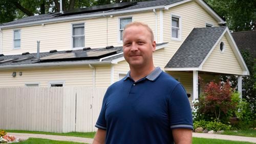 Jason Benedict poses with solar panels on his home in Berkley, Mich., Wednesday, July 24, 2024. (AP Photo/Paul Sancya)