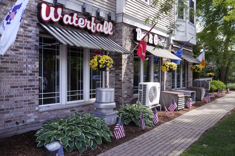 FILE - Flags fly outside the Waterfall Bar & Grille, Thursday, June 27, 2024, in Canton, Mass. Video evidence presented in the trial of Karen Read, showed the Waterfall as the last place where Read and her boyfriend John O'Keefe were seen together in public. A judge declared a mistrial Monday, July 1, 2024, after jurors deadlocked in the case of Read, who was accused of killing her police officer boyfriend, O'Keefe, by striking him with her SUV and leaving him in a snowstorm. (AP Photo/Charles Krupa, File)