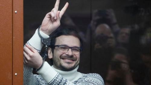 FILE - Russian opposition activist and former municipal deputy of the Krasnoselsky district Ilya Yashin gestures, smiling, as he stands in a defendant's cubicle in a courtroom, prior to a hearing in Moscow, Russia, on Dec. 9, 2022. Ilya Yashin, a prominent Kremlin critics who is serving an 8 1/2-year sentence for criticizing Russia's war in Ukraine, has been taken away from his prison to an unknown destination, his lawyer said Tuesday. (Yury Kochetkov/Pool via AP, Pool, File)