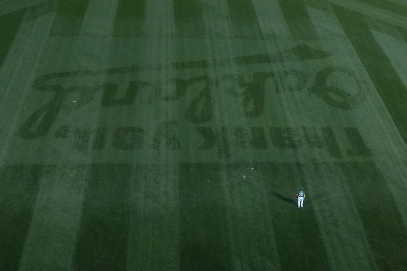 Oakland Athletics center fielder Daz Cameron stands behind a message reading "Thank You Oakland" in the outfield grass during the second inning of a baseball game against the Texas Rangers in Oakland, Calif., Wednesday, Sept. 25, 2024. (AP Photo/Jeff Chiu)