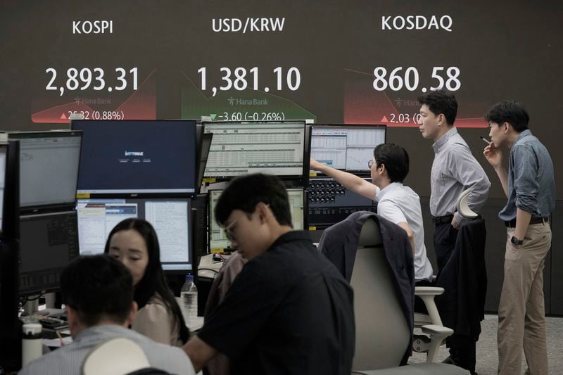 Currency traders work near the screen showing the Korea Composite Stock Price Index (KOSPI), top left, and the foreign exchange rate between U.S. dollar and South Korean won, top center, at the foreign exchange dealing room of the KEB Hana Bank headquarters in Seoul, South Korea, Thursday, July 11, 2024. (AP Photo/Ahn Young-joon)