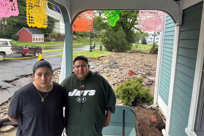 Isabel Perez and Javier Santos, owners of La Terraza Mexican Grill in Oxford, Conn., stand by their restaurant, Monday, Aug. 19, 2024, where the driveway washed away and the basement flooded when The Little River overflowed. (AP Photo/Dave Collins)