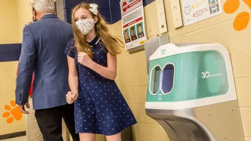 Lexi Walton, 11, finishes up her first hand washing with "Iggy", 30e Scientific's first aqueous ozone hand washing station that is installed in the Bryant Elementary School cafeteria in Mableton. The sanitation station uses ozone, a natural disinfectant, to clean elementary school hands in seven seconds before students pick up their school lunches.  The Cobb County School District and the makers of the three sanitation systems installed at the school share information before moving into demonstrates of the technologies Wednesday, Oct 21, 2020.  (Jenni Girtman for The Atlanta Journal-Constitution)