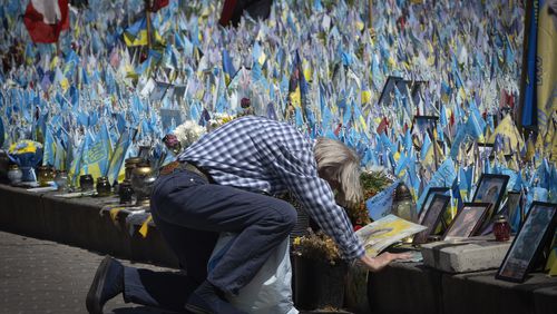 A man kneels in front of a makeshift memorial for fallen Ukrainian soldiers on Independence Square in Kyiv, Ukraine, Tuesday, July 23, 2024. Each flag brought by relatives bears a name of a soldier killed in battle with Russian troops. (AP Photo/Efrem Lukatsky)