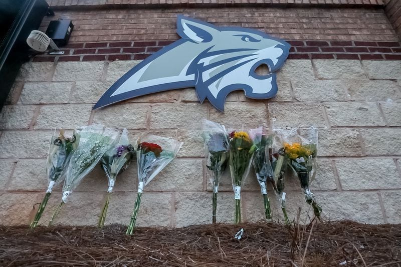 Flowers are lain at the foot of the welcome sign to Apalachee High School for a makeshift memorial Thursday morning, a day after two students and two teachers were gunned down. Nine others were injured. (John Spink/AJC)