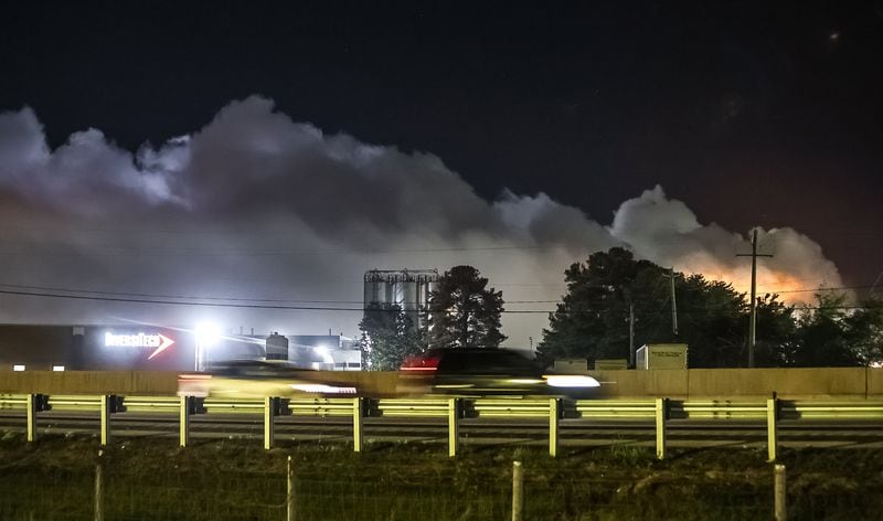 Cars travel along I-20 early Thursday morning, as a plume from the Conyers chemical plant lingers in the air.