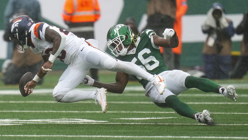 New York Jets linebacker Quincy Williams (56) knocks the ball loose for a fumble by Denver Broncos running back Tyler Badie (28) during the first quarter of an NFL football game, Sunday, Sept. 29, 2024, in East Rutherford, N.J. (AP Photo/Seth Wenig)