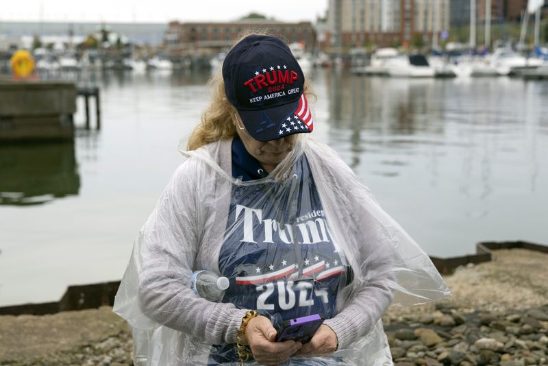 Ann Turner of Conneaught, Ohio, checks her phone as she waits in line to enter the Bayfront Convention Center before an afternoon campaign rally with Republican presidential nominee former President Donald Trump in Erie, Pa., Sunday, Sept. 29, 2024. (AP Photo/Rebecca Droke)