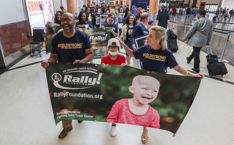 September 20, 2019  Hartsfield-Jackson International Airport: Airport: Dr. Kofi Smith, President & CEO, Atlanta Airlines Terminal Company (left) Sara Breneman-12, a cancer patient from Newnan, Georgia (center) and Dean Crowe, Founder & CEO, Rally Foundation for Childhood Cancer Research (right) march through the South Terminal Friday. The canopies turned gold Friday night, Sept. 20, 2019 and will remain that way until September 23rd at Hartsfield- Jackson International Airport in honor of childhood cancer awareness. Airport and airline partners, City dignitaries along with families fighting childhood cancer, survivors and supporters rallied in the South Terminal on Friday where presentations were made to dozens of supporters. After the presentation, the group held a âRally Walkâ around the domestic terminal in parade form, wearing the #GOLDSTRONG shirts and holding posters to bring awareness to childhood cancer. Governor Kempâs Proclamation, proclaiming September as Childhood Cancer Awareness Month in Georgia was acknowledged and a statement from Senator Johnny Isakson was read. Childhood cancer is the #1 disease killer of kids ages 0 to 15. Rally Foundation for Childhood Cancer Research (Rally), a 501(c)(3) nonprofit organization, empowers volunteers across the country to raise awareness and funds for childhood cancer research. JOHN SPINK/JSPINK@AJC.COM