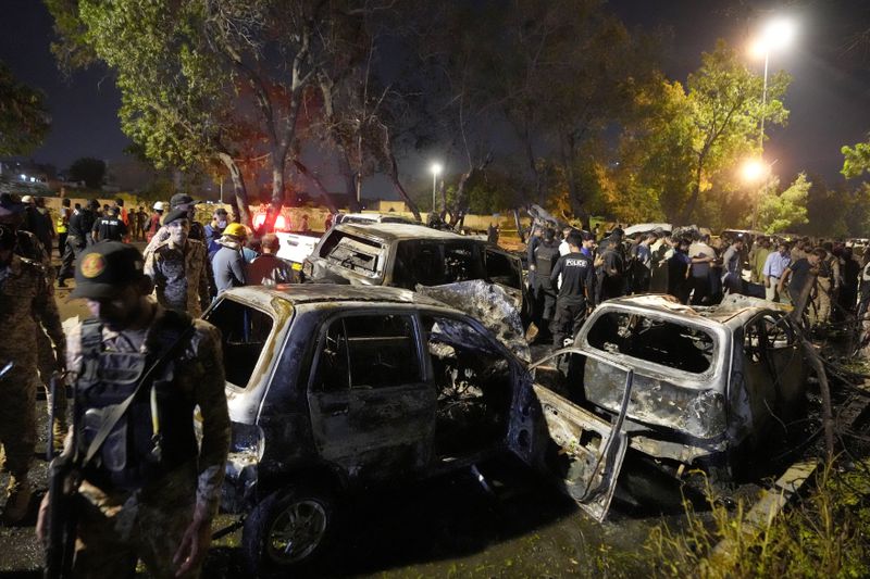 Security officials examine the site of an explosion that caused injures and destroyed vehicles at outside the Karachi airport, Pakistan, Monday, Oct. 7, 2024. (AP Photo/Fareed Khan)