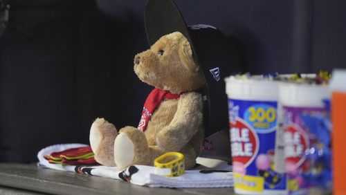 The "Snit Bear" sits in the Atlanta Braves dugout before a baseball game against the New York Yankees, Saturday, June 22, 2024, in New York. "Snit Bear" has become a presence on the team's bench, a stuffed animal with a red bandana around its neck and an oversized blue and white Braves' cap. The toy was given to Marcell Ozuna by manager Brian Snitker. (AP Photo/Frank Franklin II)