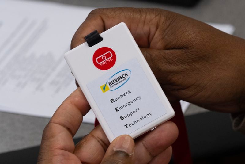 An attendee at an election security training session at Cobb County Emergency Management headquarters examines a card with a panic button on it that will be used by Cobb County election worker Aug. 23, 2024, in Marietta. (AP Photo/John Bazemore)