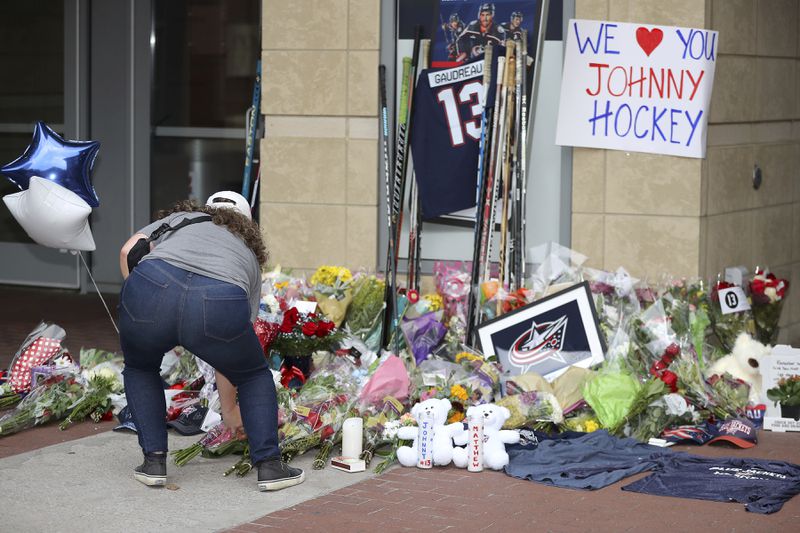 Kaitlin O'Hara of Columbus, places flowers at a memorial set up by fans for Blue Jackets hockey player Johnny Gaudreau in Columbus, Ohio, Aug. 30, 2024. Gaudreau, along with his brother Matthew, was fatally struck by a motorist while riding his bicycle on Thursday. (AP Photo/Joe Maiorana)