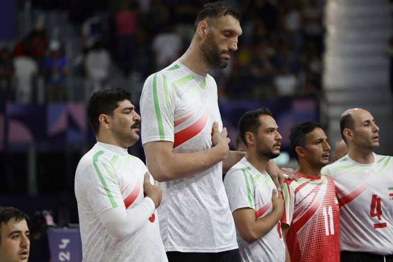 Irans's Morteza Mehrzadselakjani, fourth from right, stands with his teammates on the men's sitting volleyball team as the Iranian national anthem plays before their preliminary game against Brazil during the Paralympic Games in Paris, Sunday, Sept. 1, 2024. Iran won the game in straight sets. (AP Photo/Avni Trivedi)