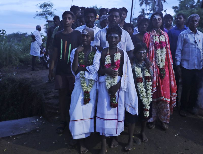 Children wear ceremonial clothes as they wait for the cremation of their parents, both of whom died after drinking illegally brewed liquor, in Kallakurichi district of the southern Indian state of Tamil Nadu, India, Thursday, June 20, 2024. The state's chief minister M K Stalin said the 34 died after consuming liquor that was tainted with methanol, according to the Press Trust of India news agency. (AP Photo/R. Parthibhan)