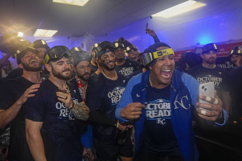 Kansas City Royals catcher Salvador Perez, right, holds a cell phone as he and teammates celebrate after defeating the Baltimore Orioles 2-1 in Game 2 of an AL Wild Card Series baseball game, Wednesday, Oct. 2, 2024 in Baltimore. (AP Photo/Stephanie Scarbrough)