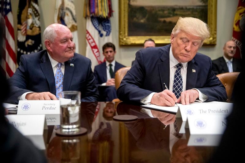 FILE - President Donald Trump, accompanied by Agriculture Secretary Sonny Perdue, signs an executive order during farmers' roundtable in the Roosevelt Room of the White House in Washington, April 25, 2017. (AP Photo/Andrew Harnik, File)