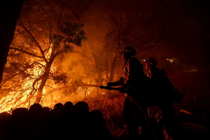 Firefighters establish a defense perimeter around a house threatened by the Bridge Fire in Wrightwood, Calif., Tuesday, Sept. 10, 2024. (AP Photo/Etienne Laurent)