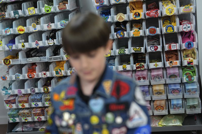 Oliver Burkhardt, 13, stands in front of trays of patches inside the offices of the Oliver Patch Project, Wednesday, Sept. 4, 2024, in Miami. (AP Photo/Rebecca Blackwell)