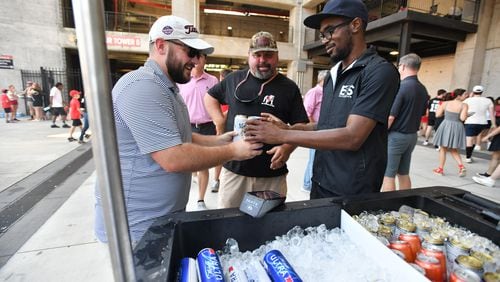 Jackson Fletcher (left) and his stepfather Todd May (center) buy beers before Georgia’s home opener against Tennessee Tech at Sanford Stadium, Saturday, September 9, 2024, in Athens. (Hyosub Shin / AJC)