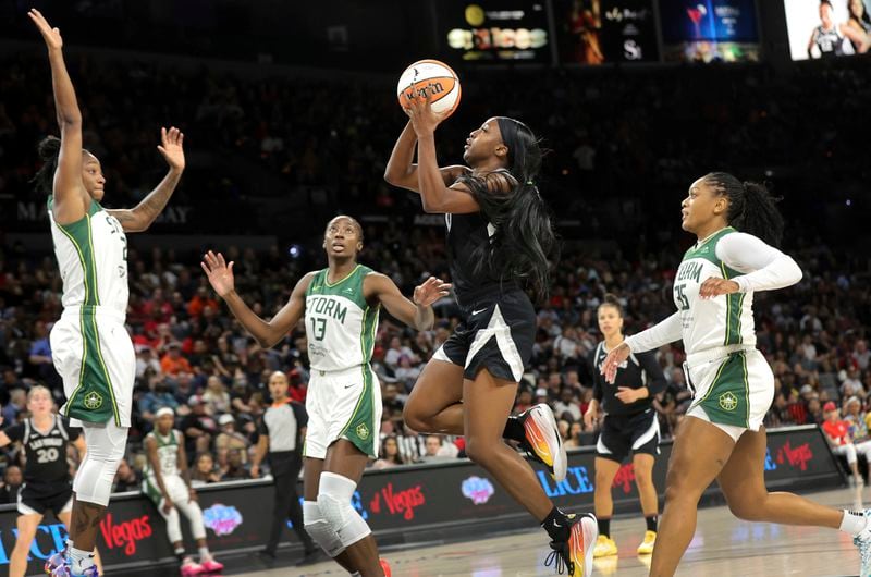 Las Vegas Aces guard Jackie Young (0) shoots a layup against Seattle Storm guard Jewell Loyd, left, center Ezi Magbegor (13) and guard Victoria Vivians (35) during the first half of an WNBA basketball game Wednesday, June 19, 2024, in Las Vegas. (Steve Marcus/Las Vegas Sun via AP)