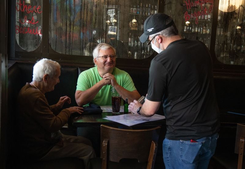 1920 Tavern employee Shane Goode (R) delivers drinks to Bart Van Linden and his mother, Sabine Van Linden, at the Roswell restaurant Monday, April 27, 2020.  STEVE SCHAEFER / SPECIAL TO THE AJC