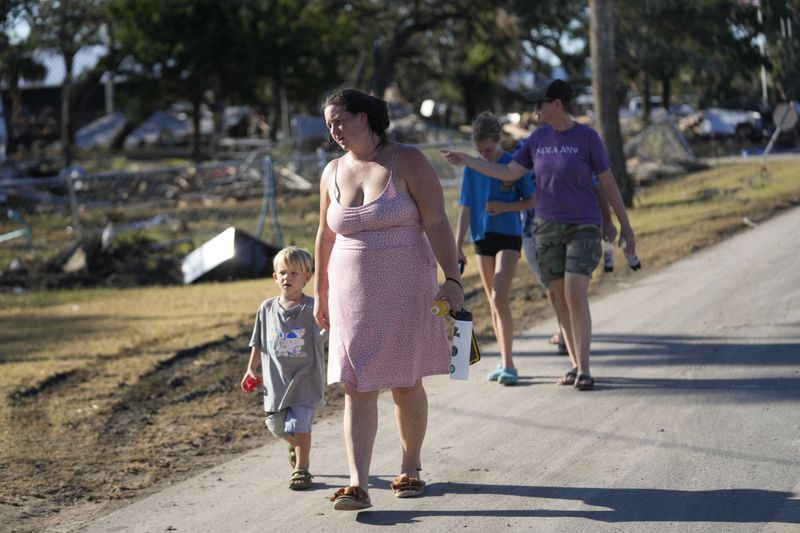 A group from St. Augustine, Fla. that arrived to help storm victims, who did not want to give their names, walk to the damaged First Baptist Church to pray in the aftermath of Hurricane Helene, in Horseshoe Beach, Fla., Sunday, Sept. 29, 2024. (AP Photo/Gerald Herbert)