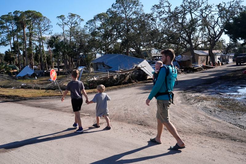 A group from St. Augustine, Fla. that arrived to help storm victims, who did not want to give their names, walk to the damaged First Baptist Church to pray in the aftermath of Hurricane Helene, in Horseshoe Beach, Fla., Sunday, Sept. 29, 2024. (AP Photo/Gerald Herbert)