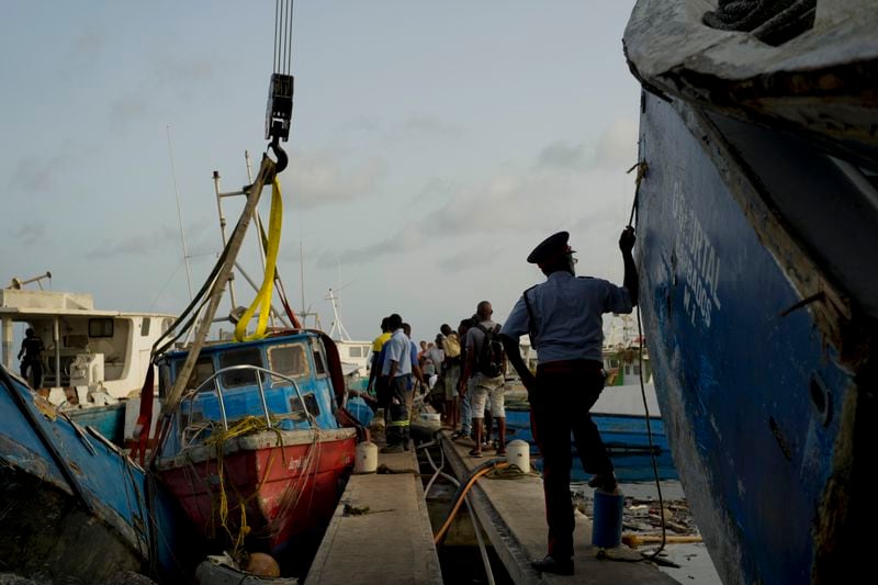 Fishermen fix up a boat damaged by Hurricane Beryl to be lifted from the Bridgetown Fisheries, Barbados, Tuesday, July 2, 2024. (AP Photo/Ricardo Mazalan)