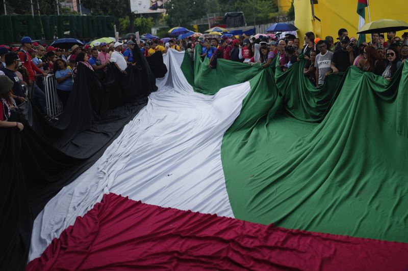 Demonstrators unfurl a Palestinian flag during march to the United Nations office in a government organized demonstration to show support for the Palestinian people in Caracas, Venezuela, Saturday, Oct. 5, 2024, days before the one-year anniversary of Hamas' attack in southern Israel and Israel's response to go to war on Hamas. (AP Photo/Ariana Cubillos)